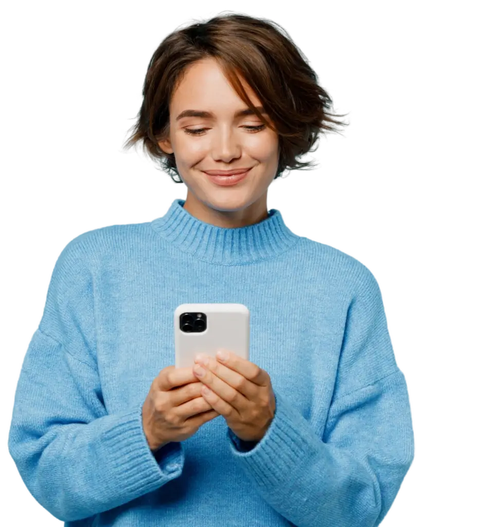 Junge Frau in einem blauen Pullover, die lächelnd auf ihr Smartphone schaut und es in den Händen hält, vor einem sanften, einfarbigen Hintergrund.