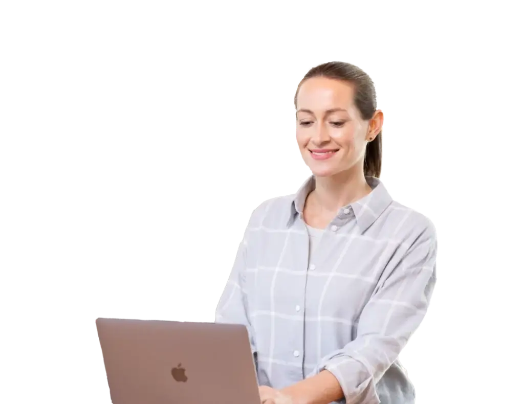 Woman with blonde hair and smiling face works on a laptop, wears a plaid shirt and is pictured in a modern work environment.