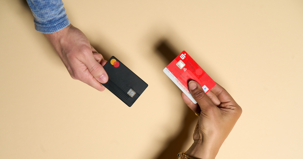 Zwei Hände halten die girocard und Kreditkarte nebeneinander. Der Unterschied ist gut erkennbar.